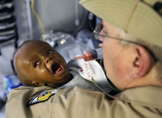 Americký lékař ošetřuje dítě v polní nemocnici.